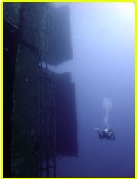 Diver scuba dives around the back doors of the Zenobia wreck