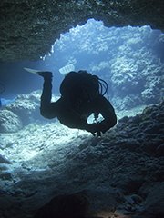 Diver silhouetted inside the cave at cyprus dive site, tunnels and caves