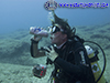 diver mimes drinking from a wine bottle found underwater